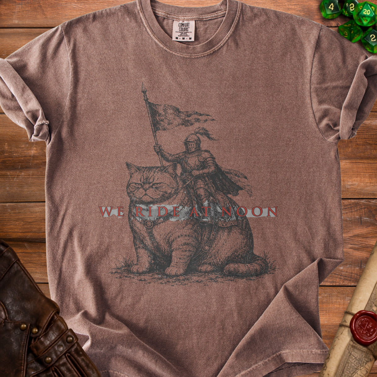 Brown t-shirt with knight on cat graphic and "WE RIDE AT NOON" text.
