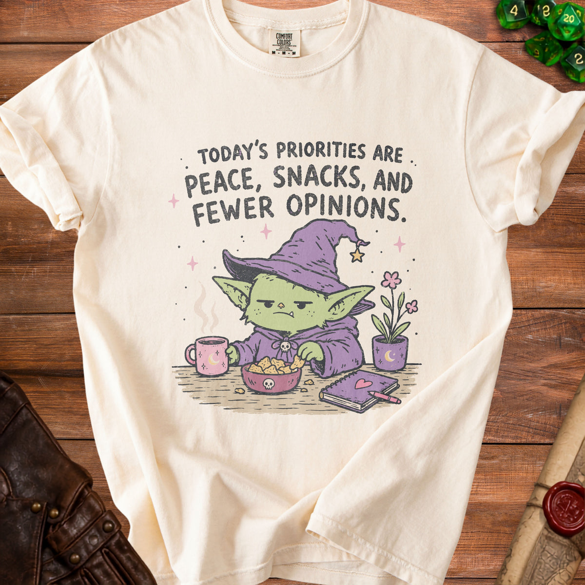 Cream t-shirt with text "Today's Priorities Are Peace, Snacks, and Fewer Opinions" and goblin graphic.