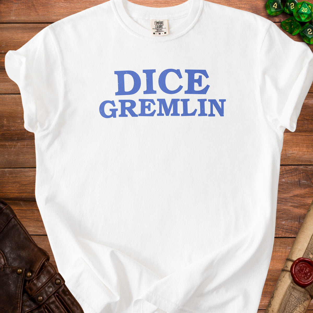 White t-shirt with blue "DICE GREMLIN" text, set against a wooden background.