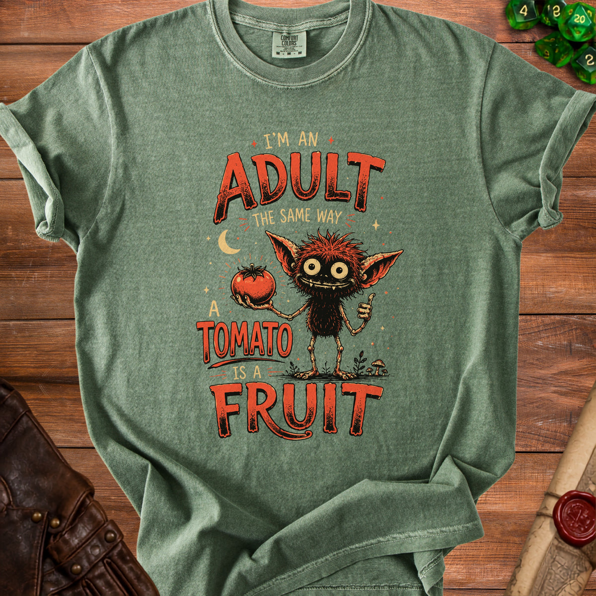 Green t-shirt with a monster holding a tomato and the text "I'm an adult the same way a tomato is a fruit."