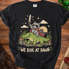 Raccoon in cape riding alligator with sword, text "We Ride At Dawn."