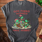 Graphic tee with red text "GOD FORBID WOMEN HAVE HOBBIES" and illustration of goblins.