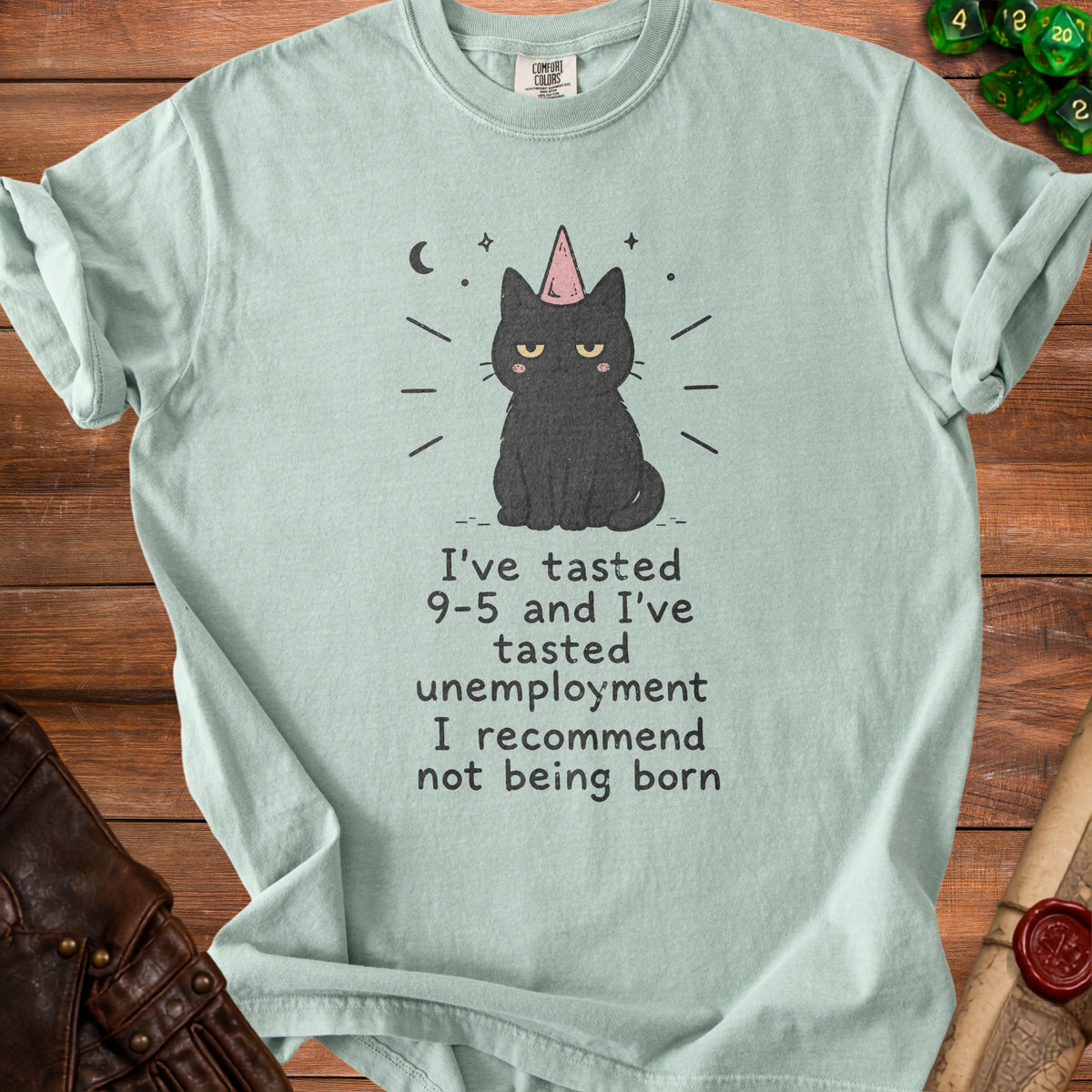 Light mint t-shirt with a black cat wearing a party hat and text.