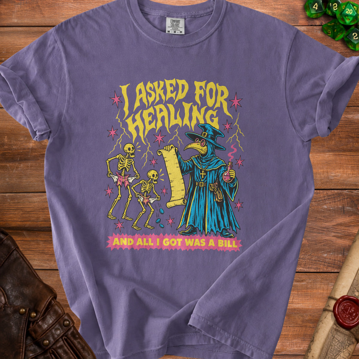 Purple t-shirt with graphic of plague doctor and skeletons saying "I asked for healing and all I got was a bill."