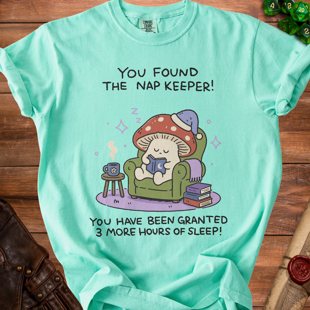 Teal t-shirt with a mushroom character reading a book, saying "You found the nap keeper!".