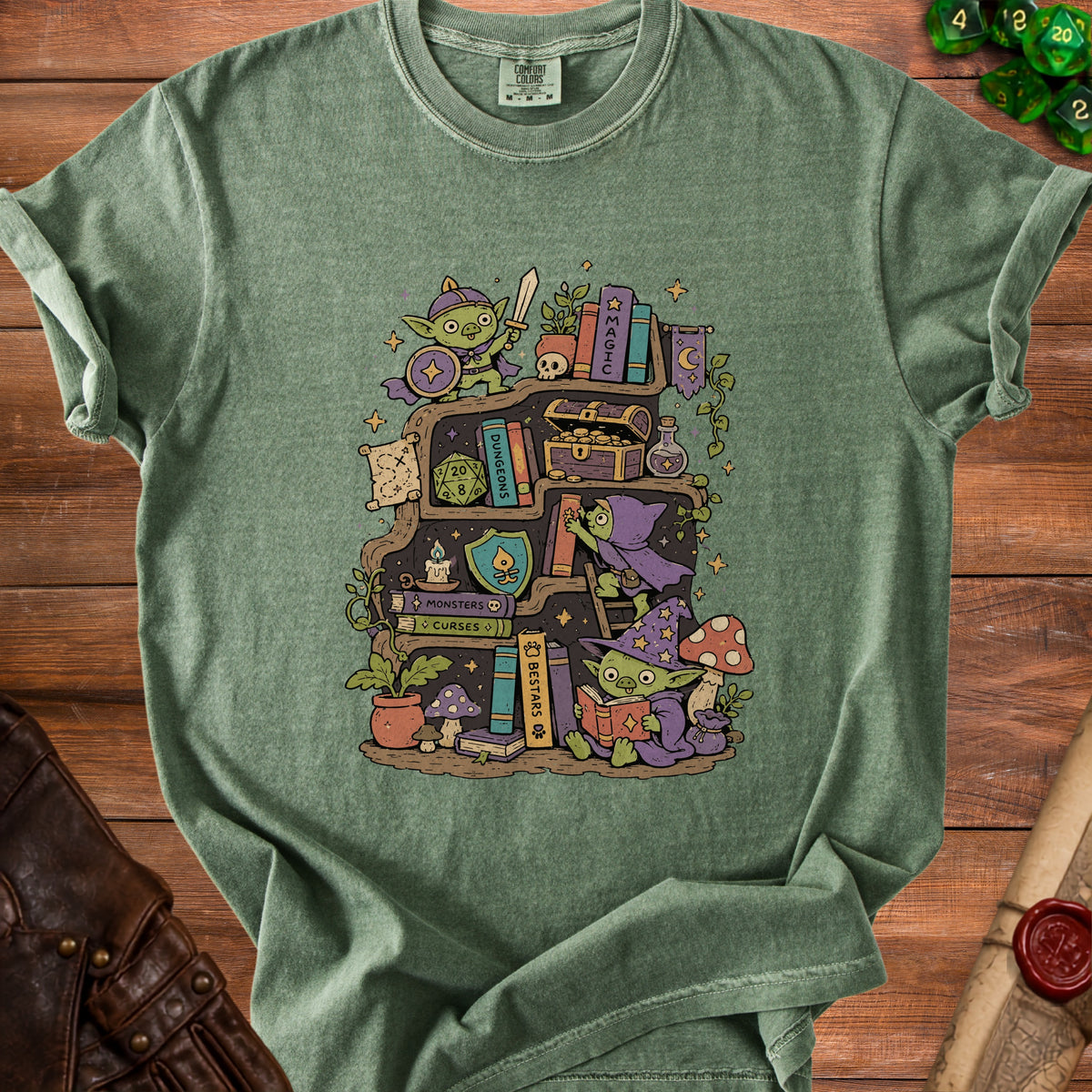 Green t-shirt with a playful goblin bookshelf illustration and dice.