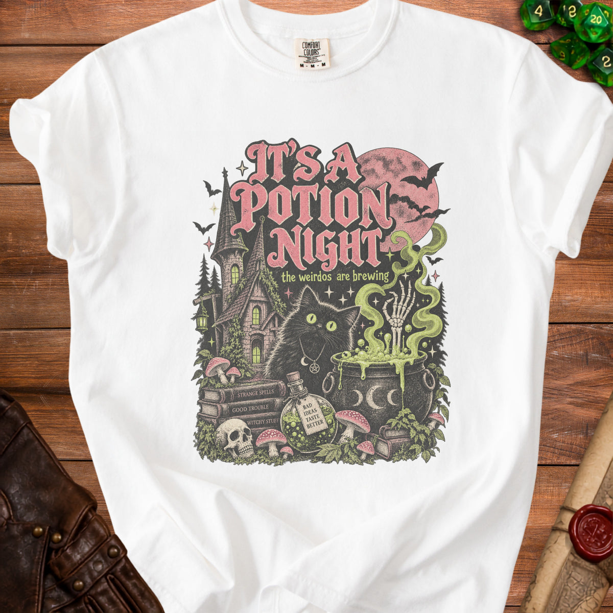 White t-shirt graphic with a black cat, potion, and spooky castle; text reads "It's a Potion Night."