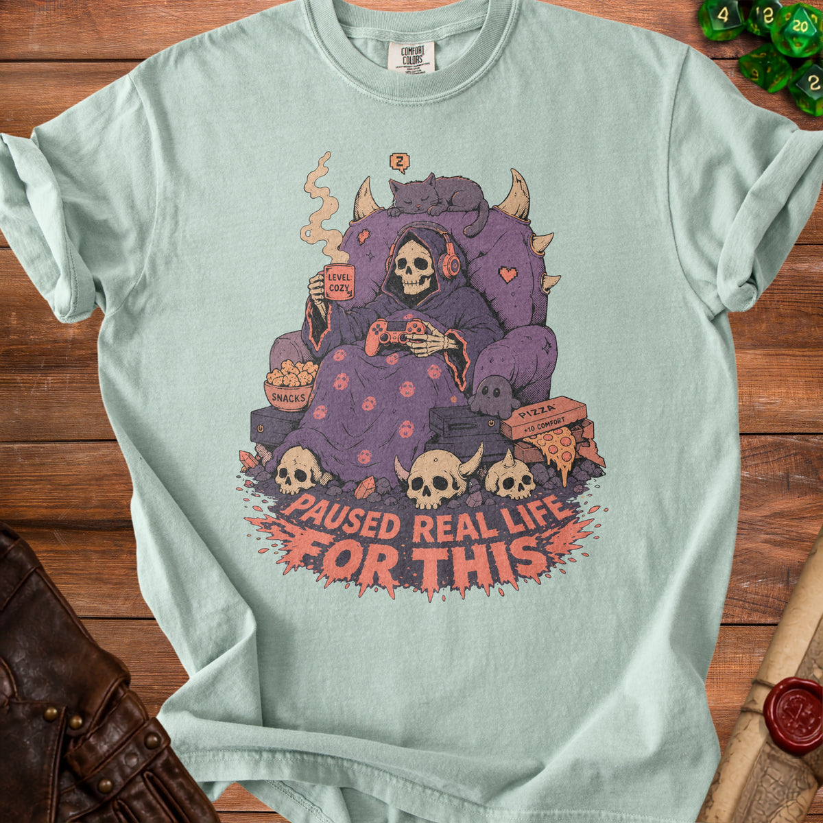 Light blue t-shirt with grim reaper playing video games and text "PAUSED REAL LIFE FOR THIS".