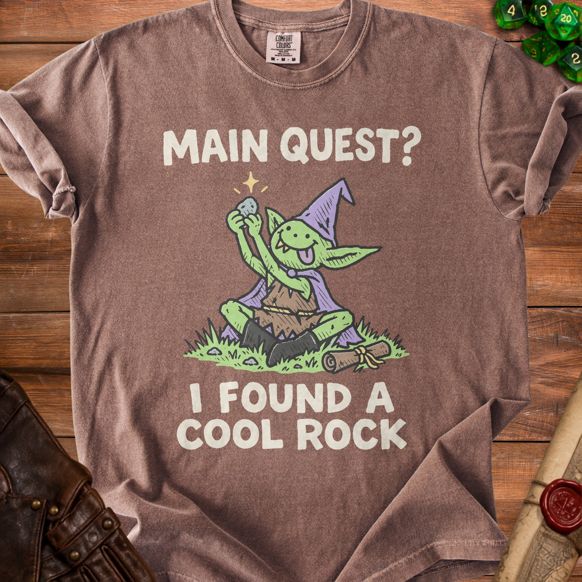 Brown t-shirt with a goblin holding a rock and text "MAIN QUEST? I FOUND A COOL ROCK."