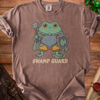Brown t-shirt with a cartoon frog wearing armor and holding a mace and shield, text reads "SWAMP GUARD".