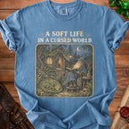 Blue t-shirt with wizard, sleeping dragon, and "A Soft Life In A Cursed World" text.