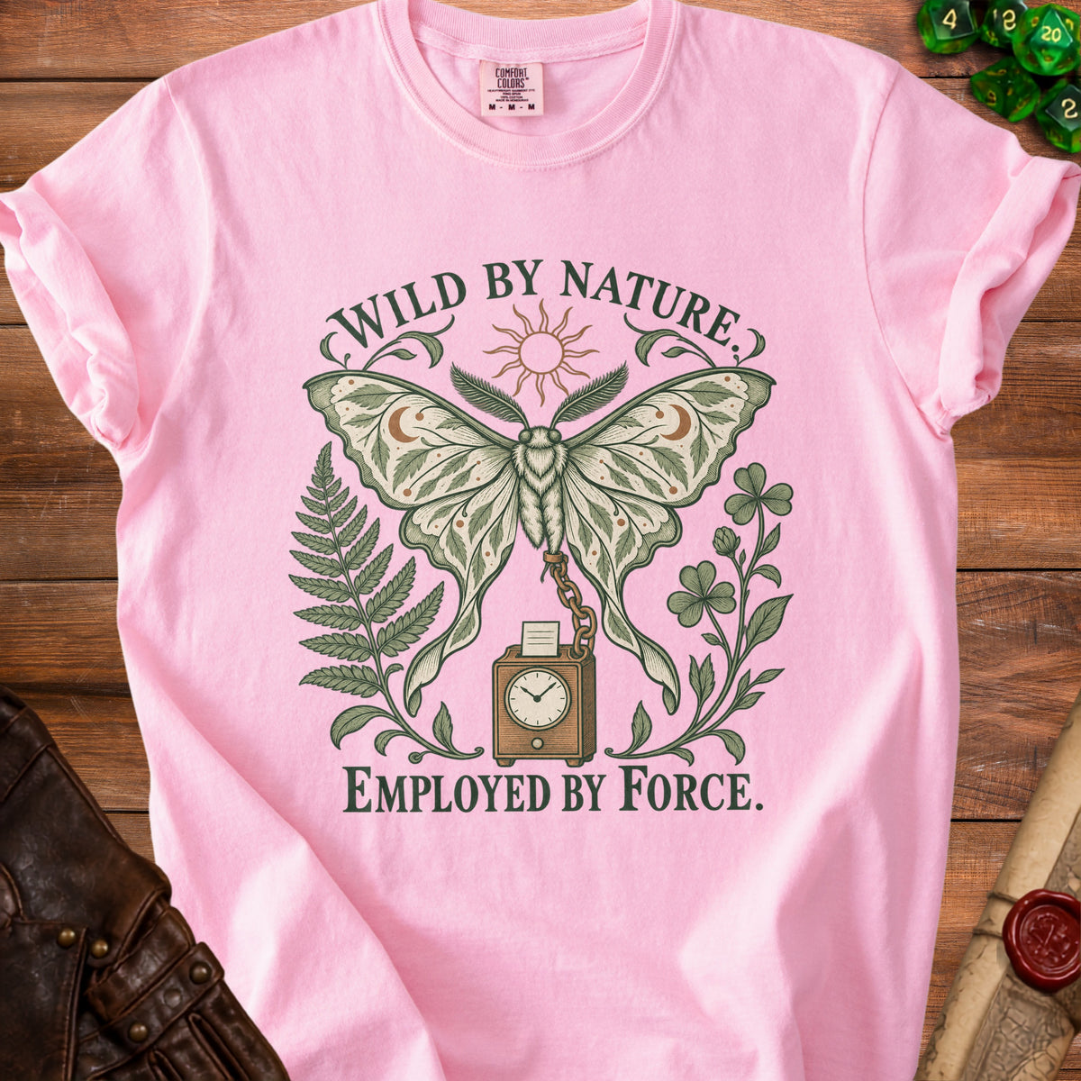 Pink t-shirt with moth, sun, ferns, and clock graphic, reading "WILD BY NATURE. EMPLOYED BY FORCE."