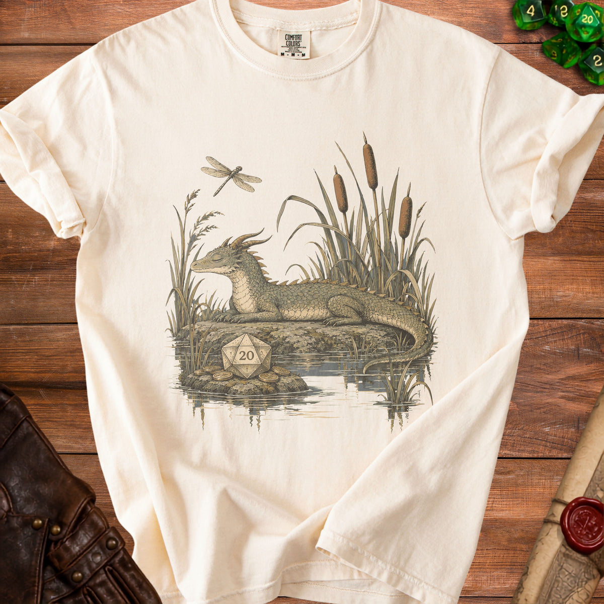 Cream t-shirt with dragon, dragonfly, and d20 die illustration by water.