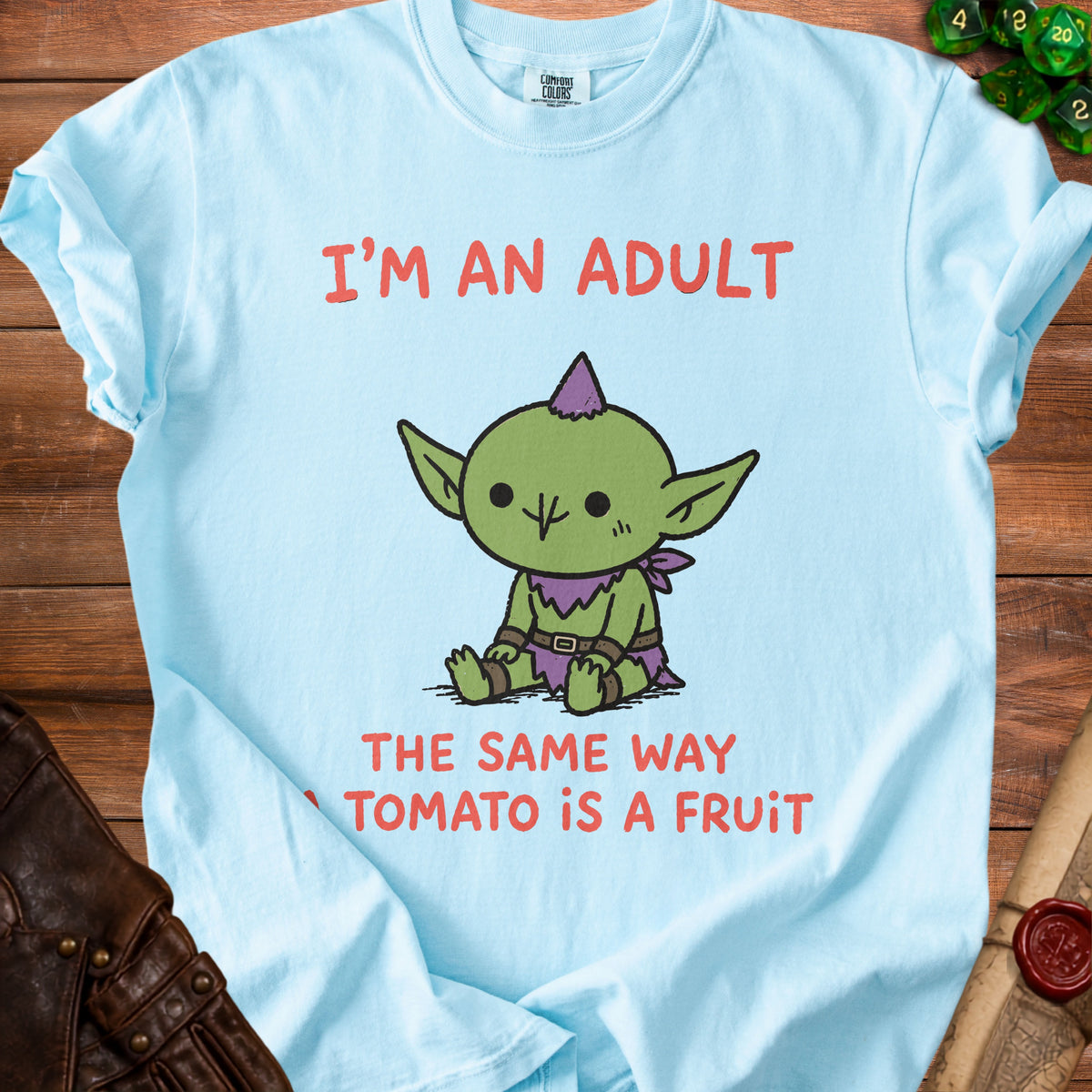 Light blue t-shirt with cartoon goblin and text: "I'M AN ADULT THE SAME WAY TOMATO IS A FRUIT."