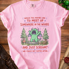 Pink t-shirt with a cartoon green dragon in woods, holding coffee.