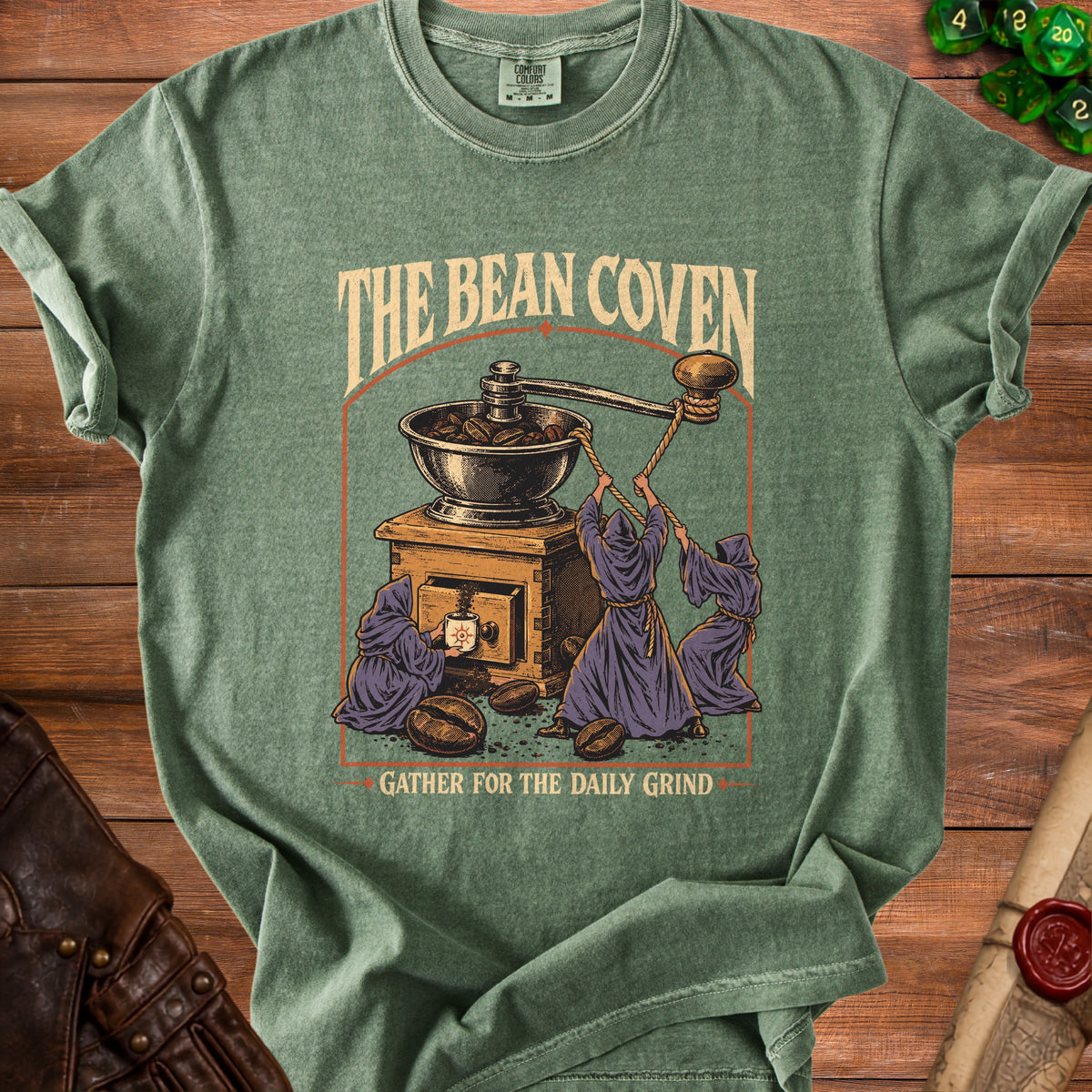 Green t-shirt with "The Bean Coven Gather for the Daily Grind" text and coffee grinder graphic.