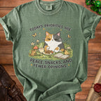 Green t-shirt with a calico cat graphic and text: "Today's priorities are peace, snacks, and fewer opinions."