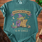Green t-shirt graphic of a goblin wizard adding doom to his scrolls.