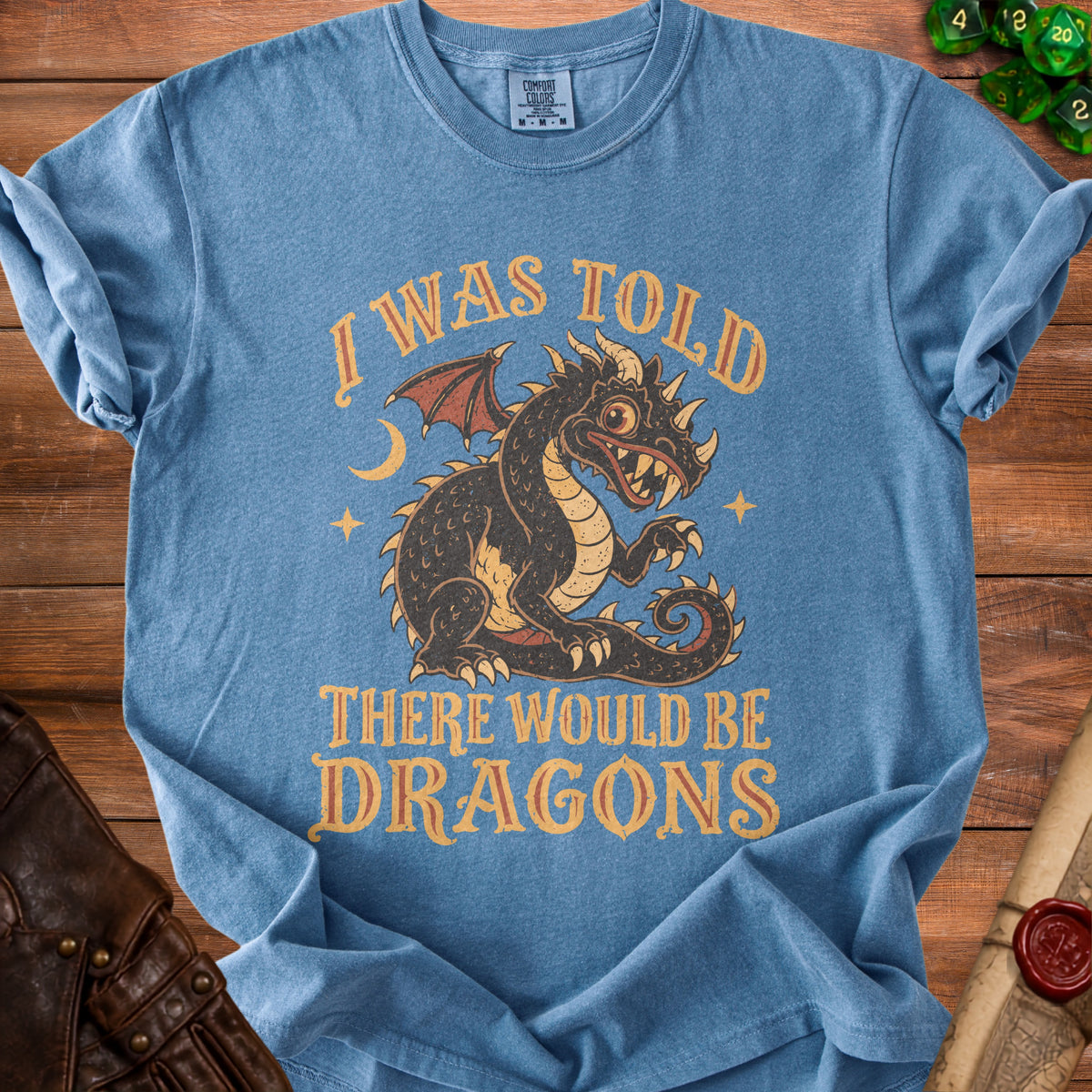 Blue t-shirt with a vintage dragon graphic and text "I WAS TOLD THERE WOULD BE DRAGONS".