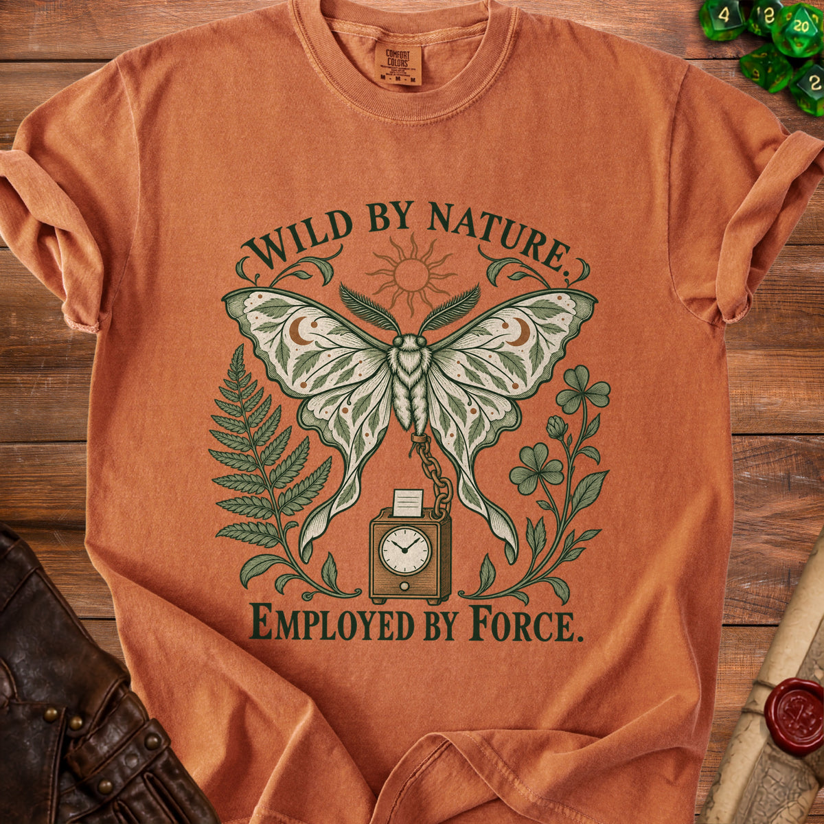 Orange t-shirt with a moth, sun, fern, clover, and clock design. Text reads "WILD BY NATURE. EMPLOYED BY FORCE."