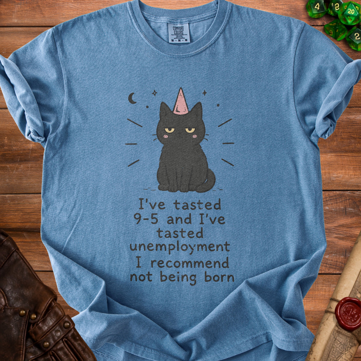 Blue t-shirt with a grumpy black cat wearing a party hat and text about 9-5 and unemployment.