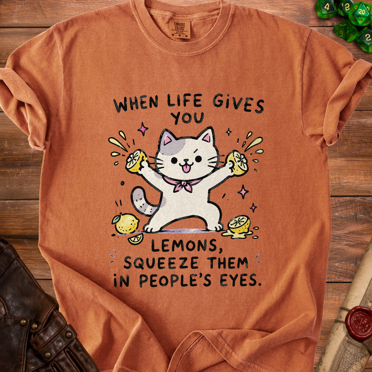 Orange t-shirt with a graphic of a cat squeezing lemons and the text "When life gives you lemons, squeeze them in people's eyes."