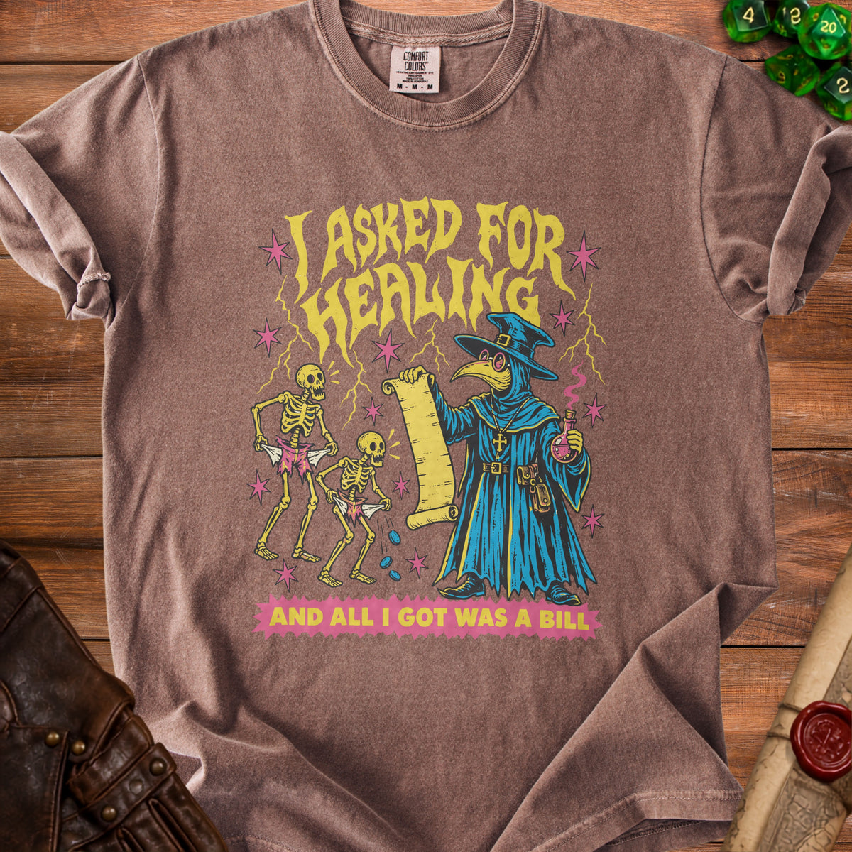 Brown t-shirt with "I ASKED FOR HEALING AND ALL I GOT WAS A BILL" and plague doctor design.