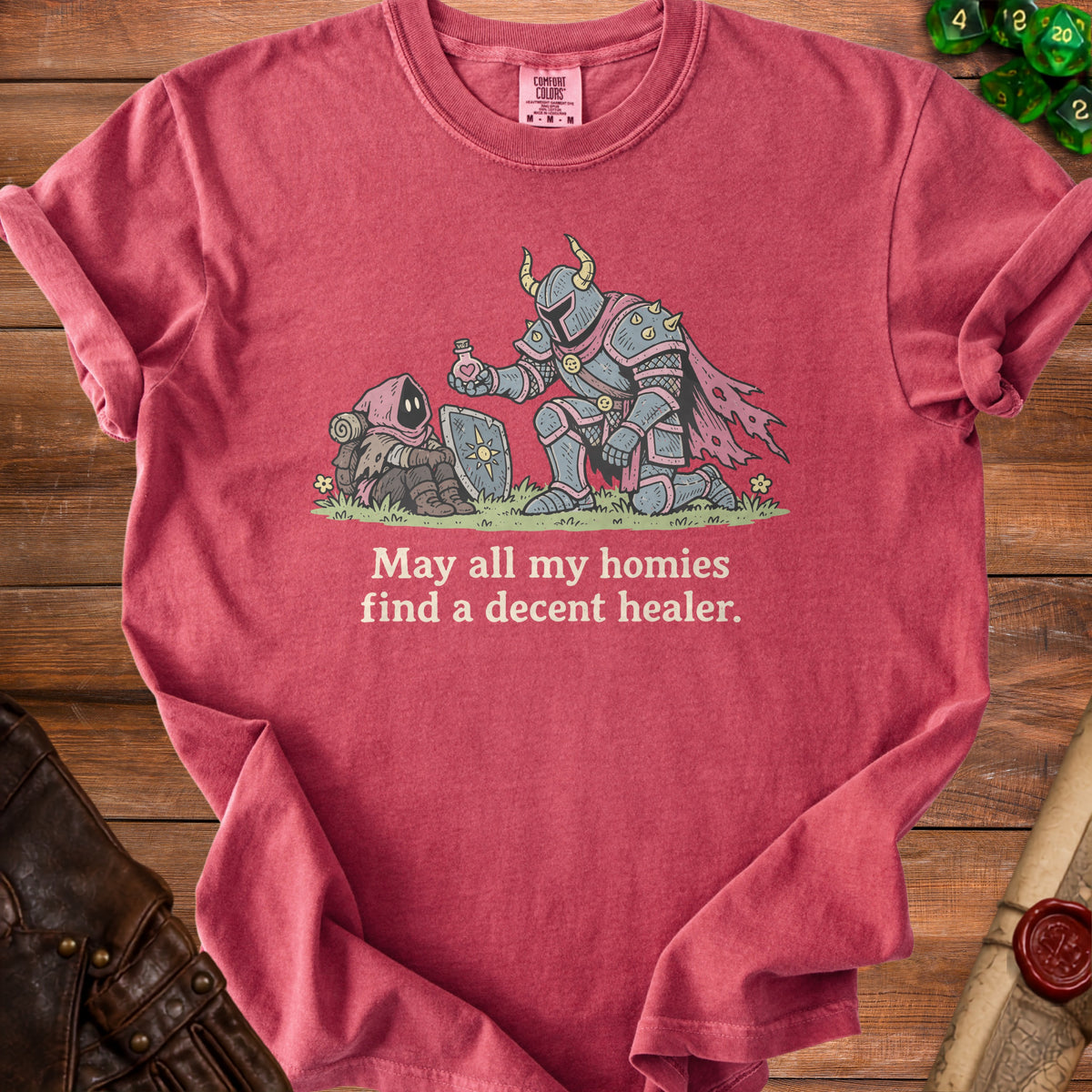 T-shirt graphic with knight offering potion to a hooded figure, text "May all my homies find a decent healer."