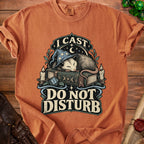 Orange t-shirt featuring a sleeping opossum in a wizard hat on a book with the text I Cast Do Not Disturb
