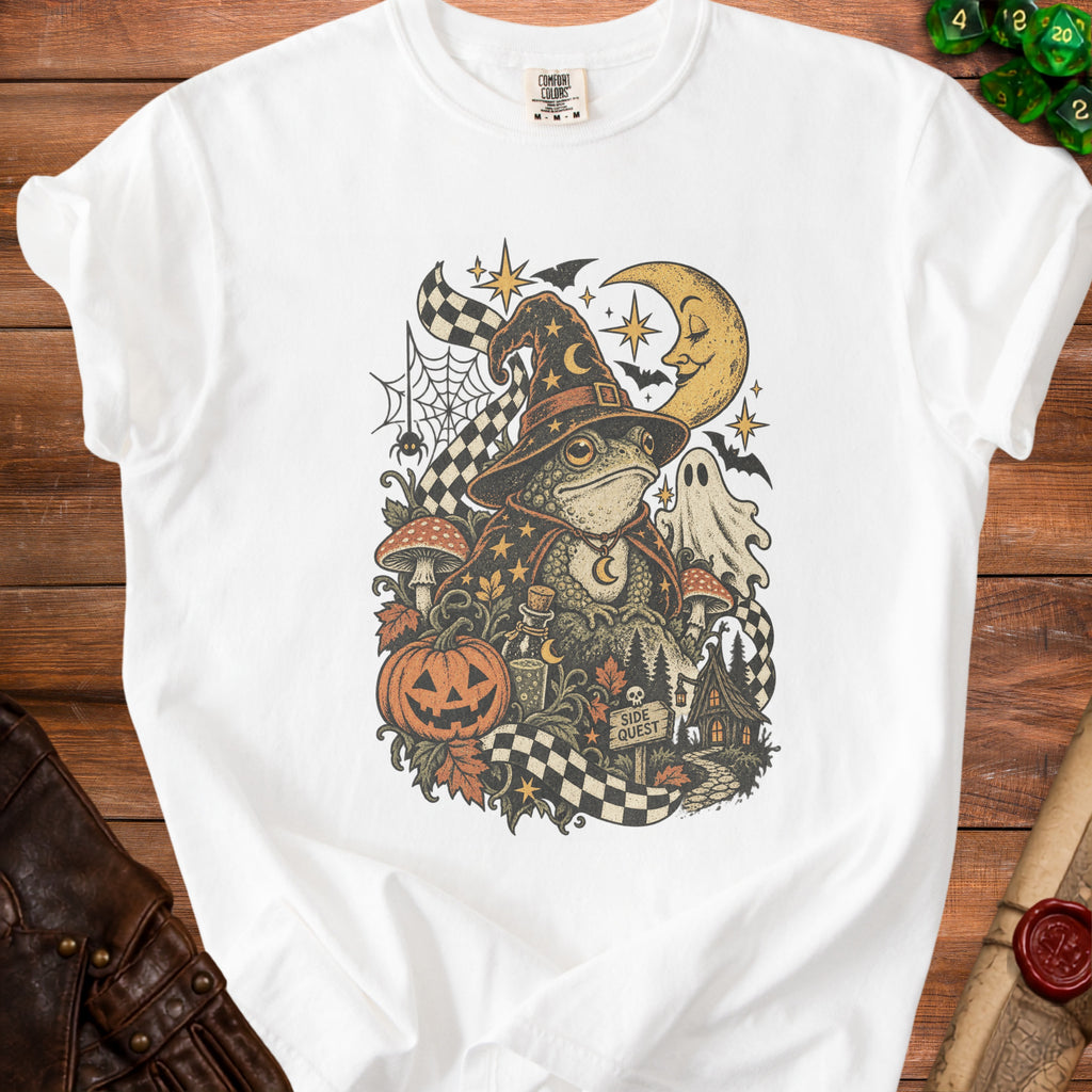 White t-shirt with vintage style Halloween graphic of a wizard frog, pumpkin, and ghost.