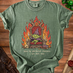 Green t-shirt with illustration of a goblin on a throne with flames and text "due to personal reasons i am evil now".
