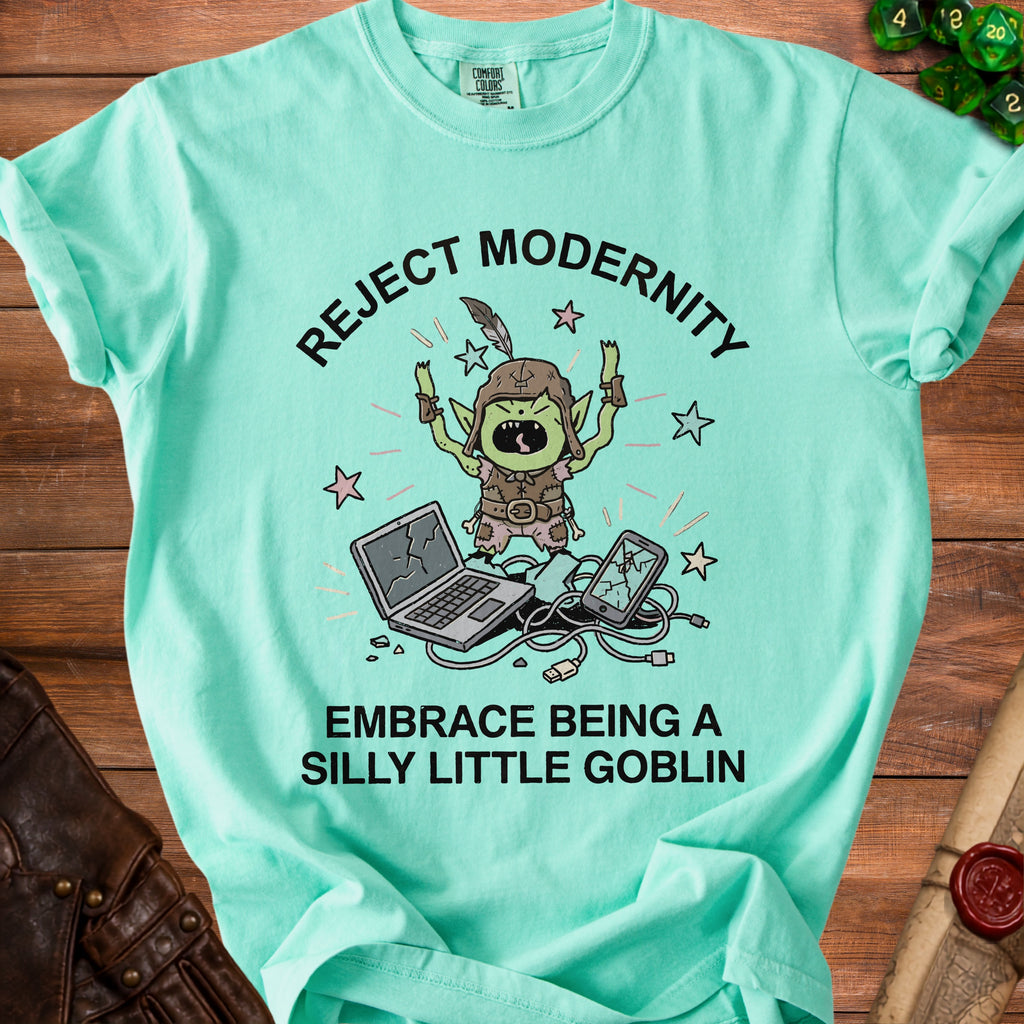 Teal t-shirt with graphic of a goblin rejecting modernity with broken tech.