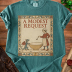 Teal t-shirt with illustration of a chef and dragon, text "A MODEST REQUEST".