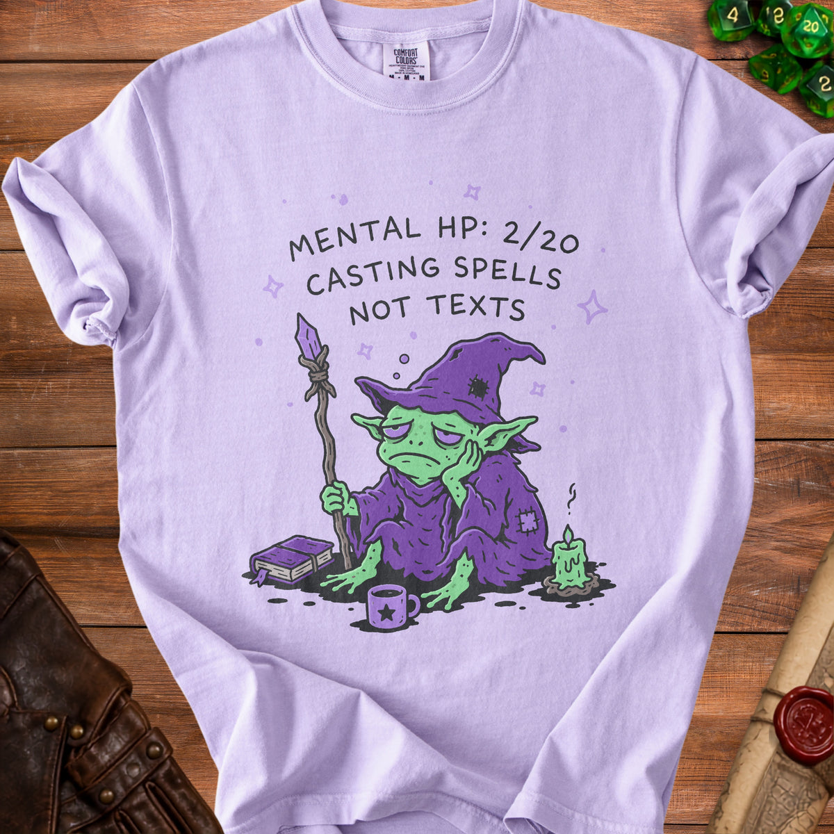 Lilac t-shirt with illustration of a sad goblin wizard and text "Mental HP: 2/20 Casting Spells Not Texts".