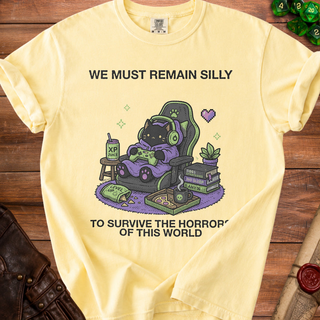 Yellow t-shirt with graphic of black cat gamer, "WE MUST REMAIN SILLY TO SURVIVE THE HORROR OF THIS WORLD".