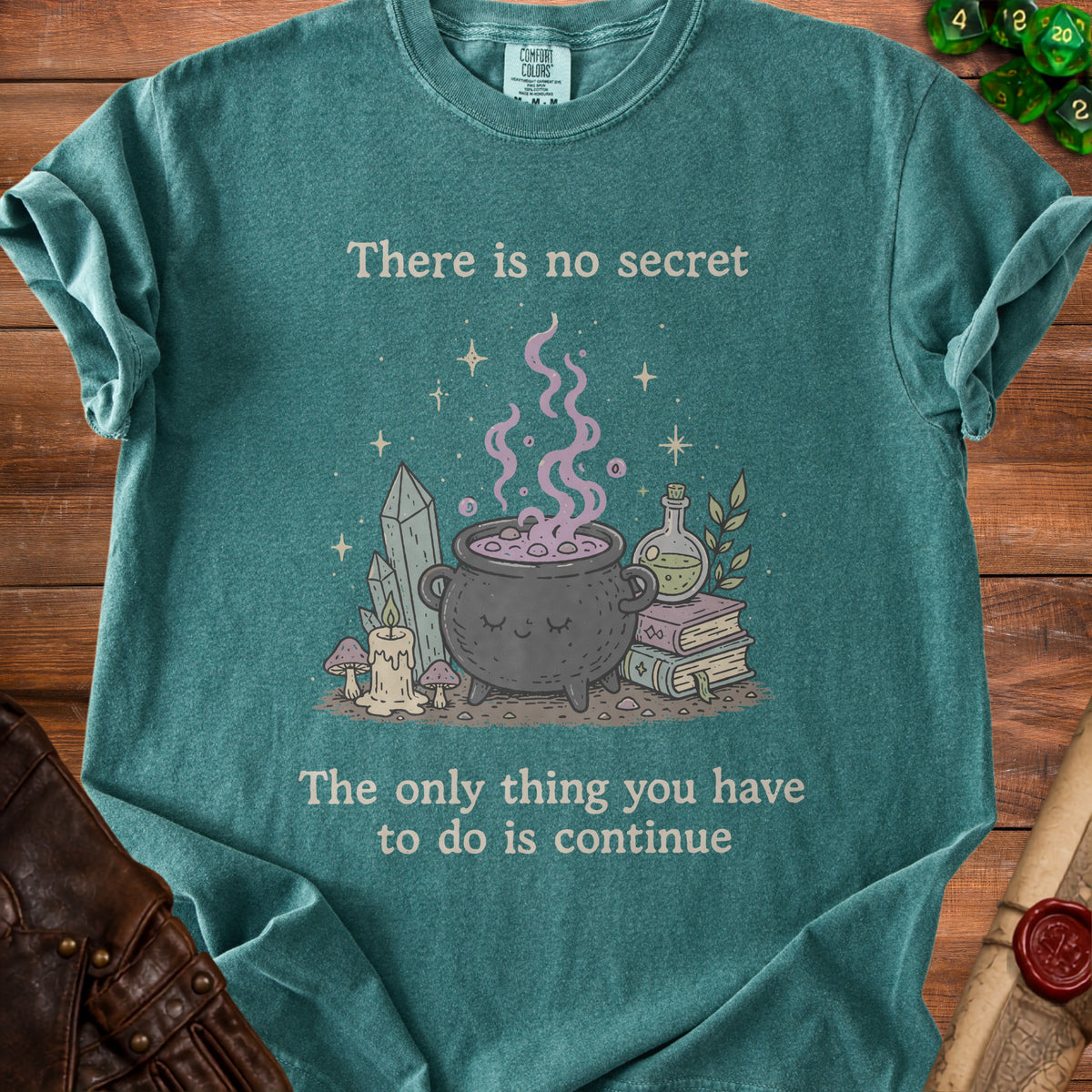 Teal t-shirt with witchy illustration and text "There is no secret The only thing you have to do is continue".