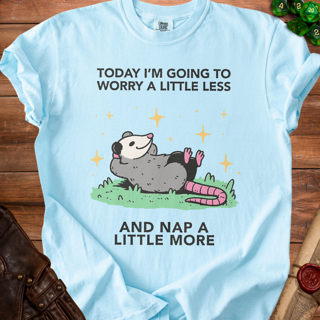Light blue t-shirt with a possum graphic and text "TODAY I'M GOING TO WORRY A LITTLE LESS AND NAP A LITTLE MORE".