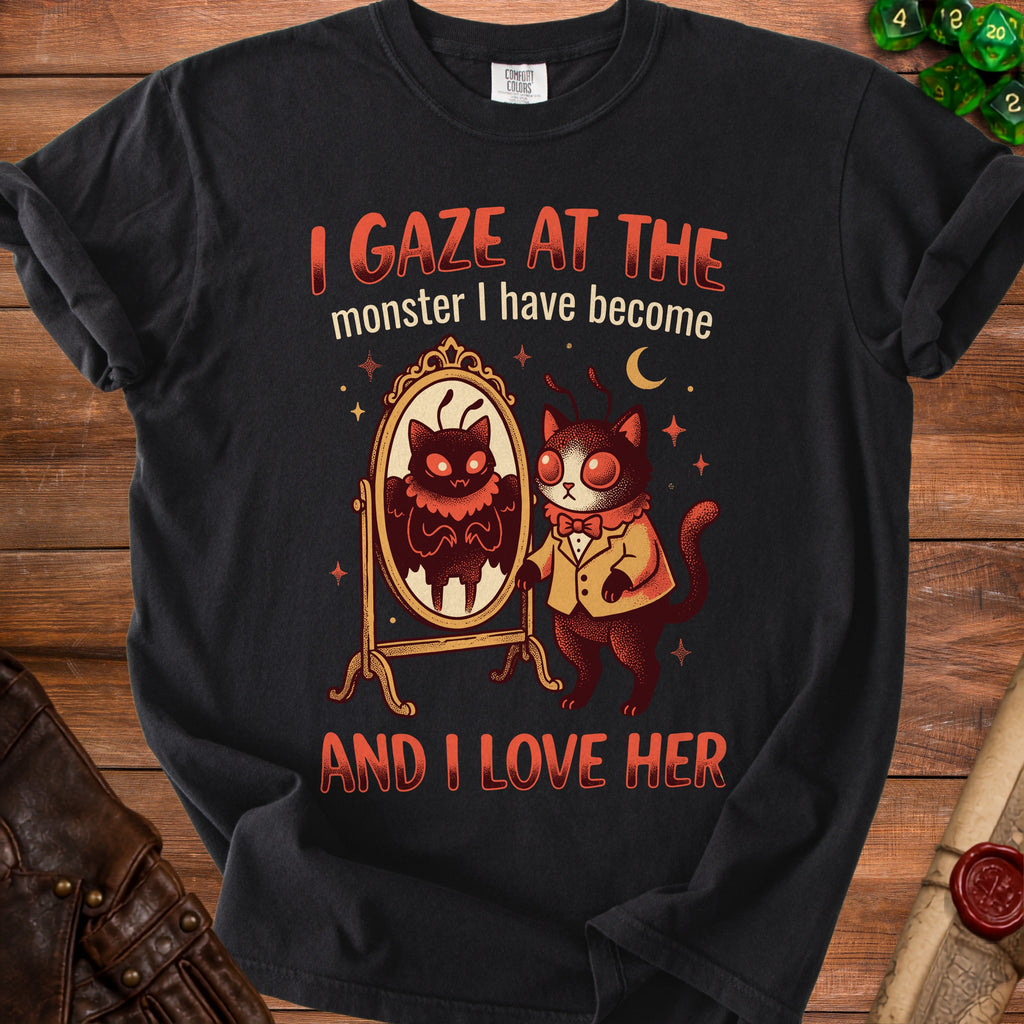 Black t-shirt with a graphic of a cat looking in a mirror at a monster and text.