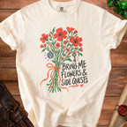 Cream t-shirt with red flowers, dice, scroll, and key, reading "Bring me flowers & side quests".