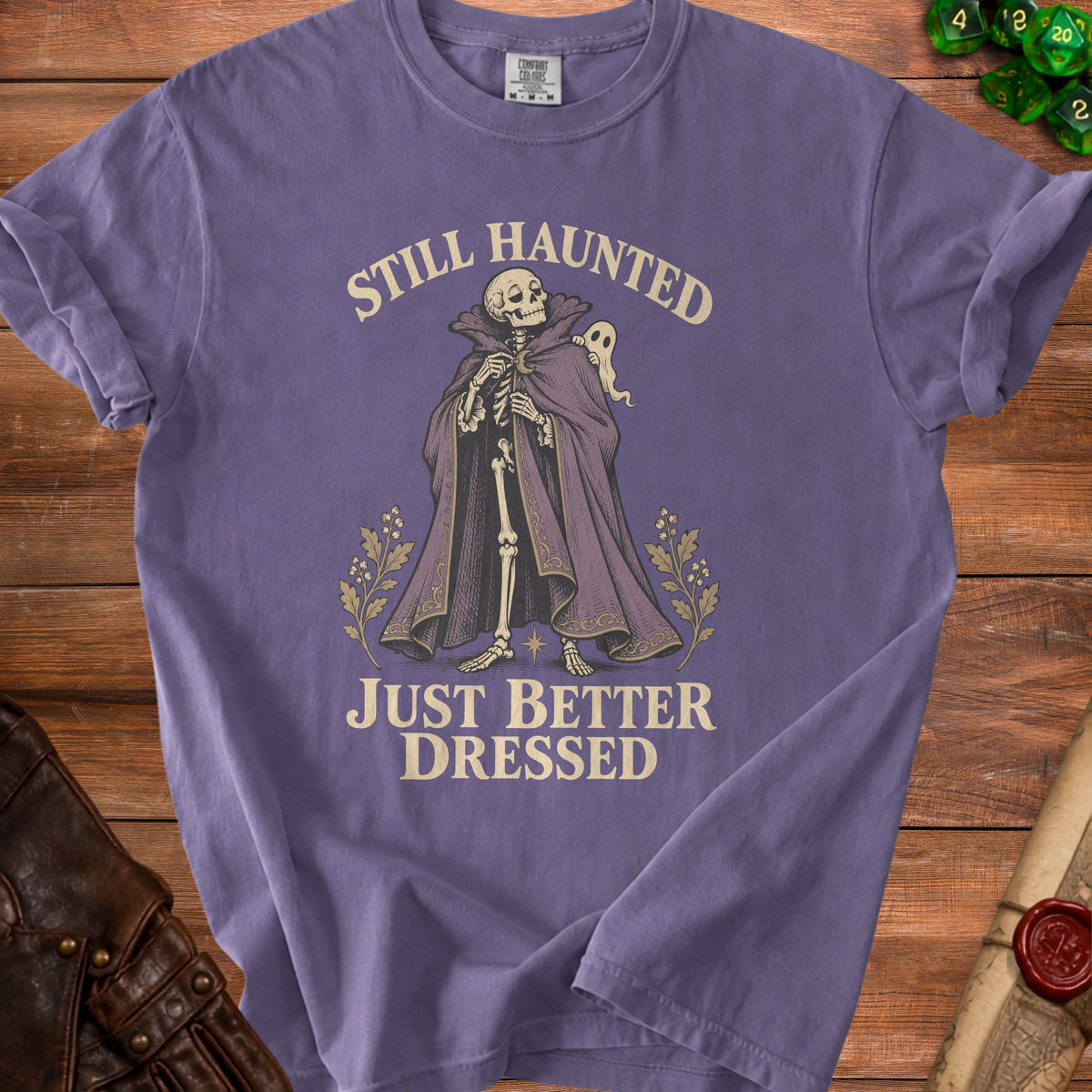 Skeleton with ghost wearing ornate cloak; text reads "STILL HAUNTED JUST BETTER DRESSED."
