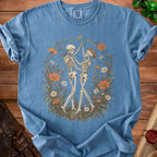 Blue crewneck t-shirt featuring a graphic of two skeletons dancing inside a floral wreath.