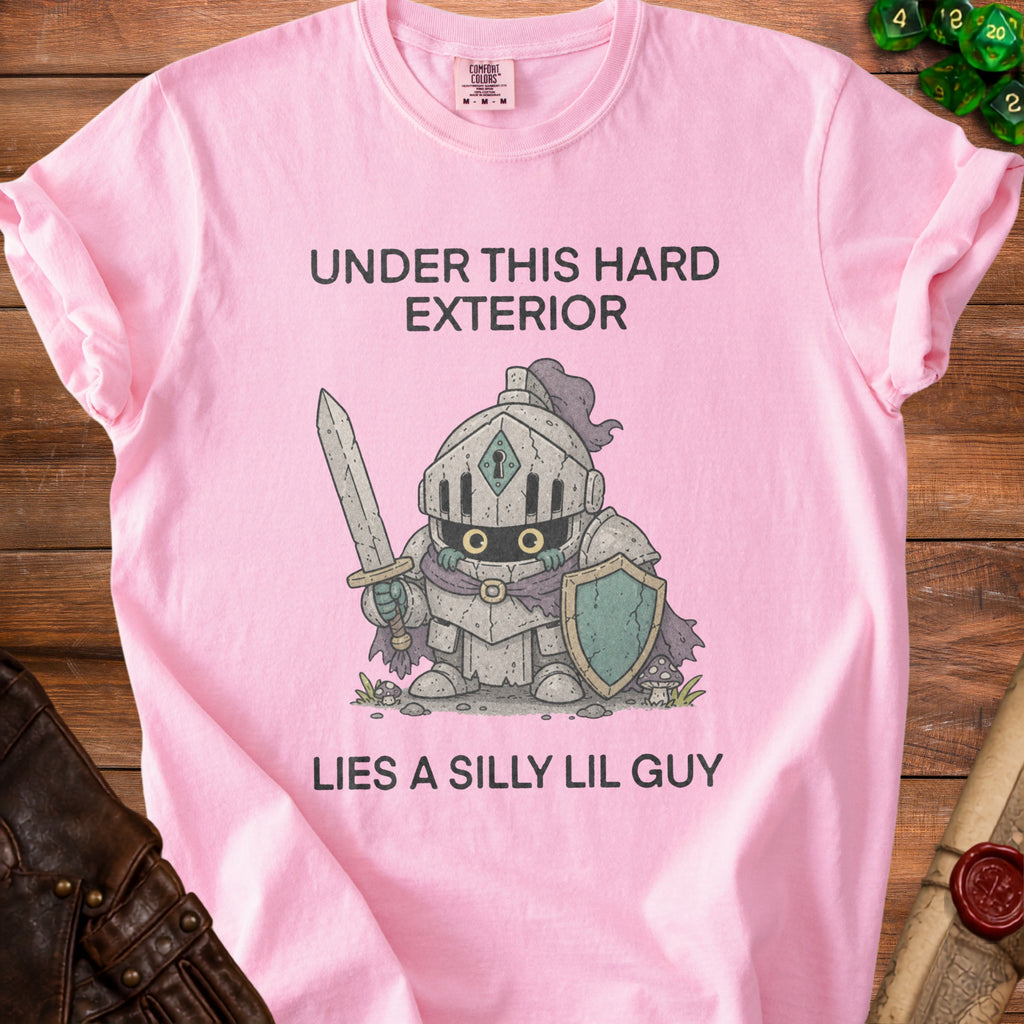 Pink t-shirt with text "UNDER THIS HARD EXTERIOR LIES A SILLY LIL GUY" and knight graphic.