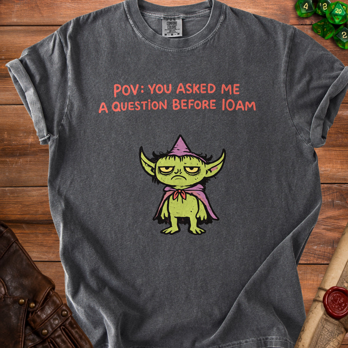 Dark grey t-shirt with text "POV: YOU ASKED ME A QUESTION BEFORE 10AM" and a grumpy green creature.