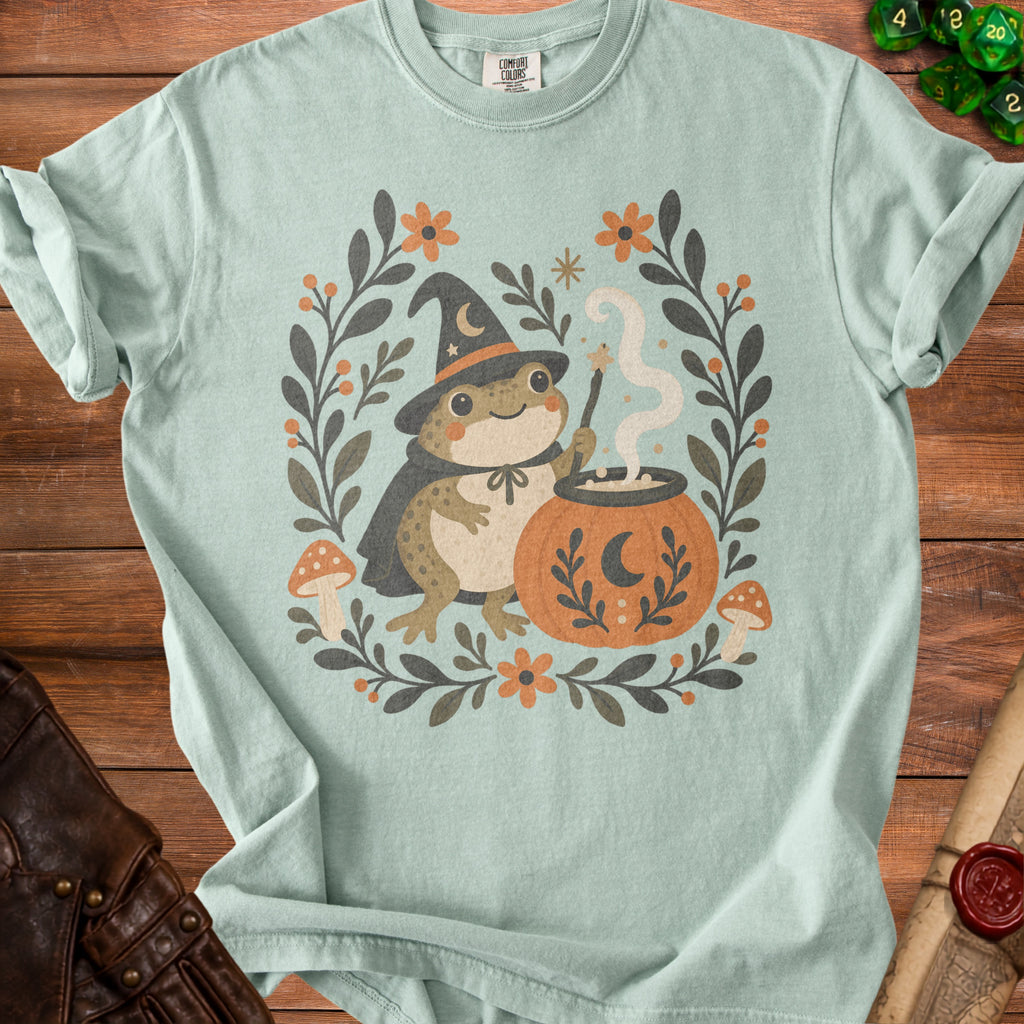 Mint t-shirt with a cute frog wizard, cauldron, pumpkin, and floral border.