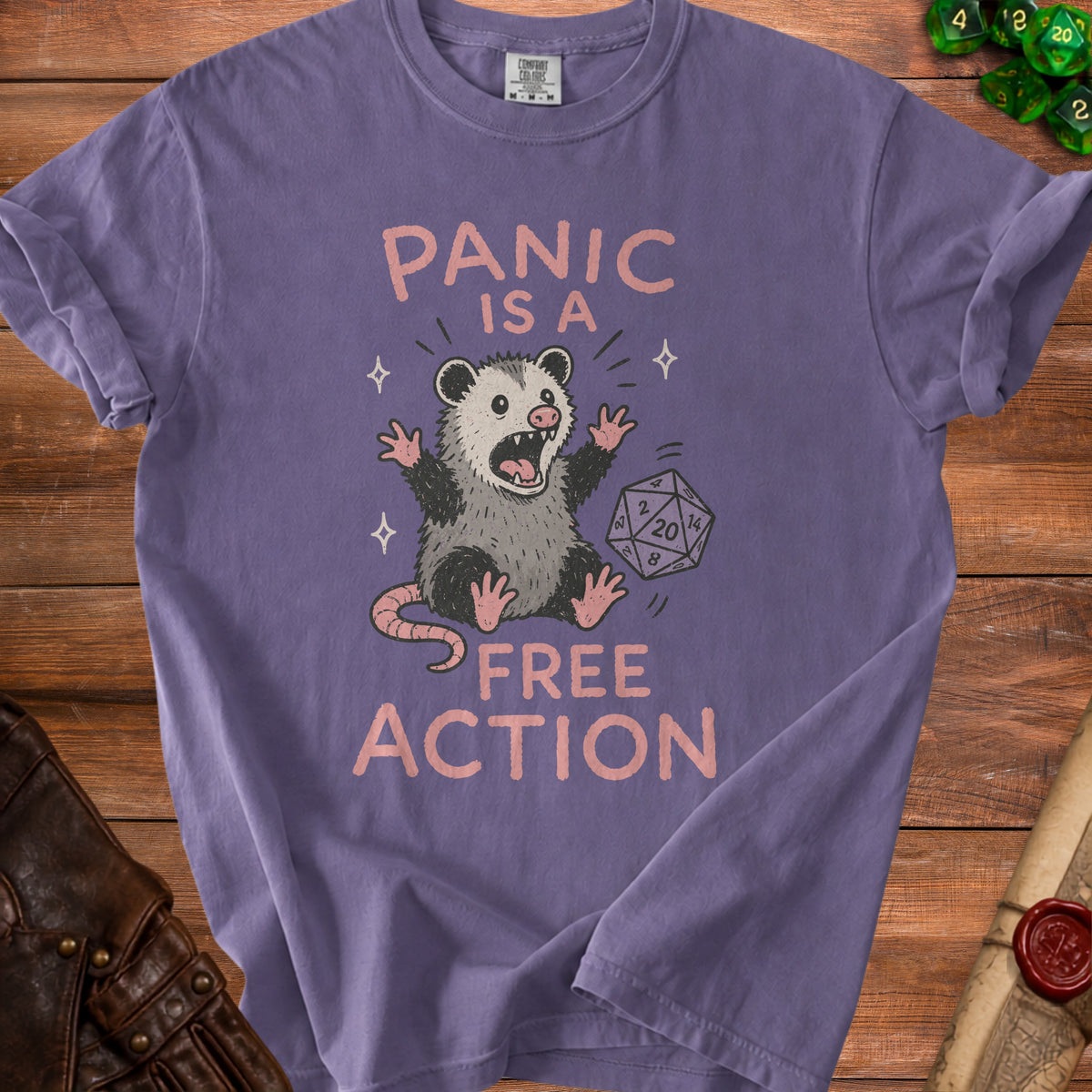 Purple t-shirt with a possum and dice graphic that reads "PANIC IS A FREE ACTION".