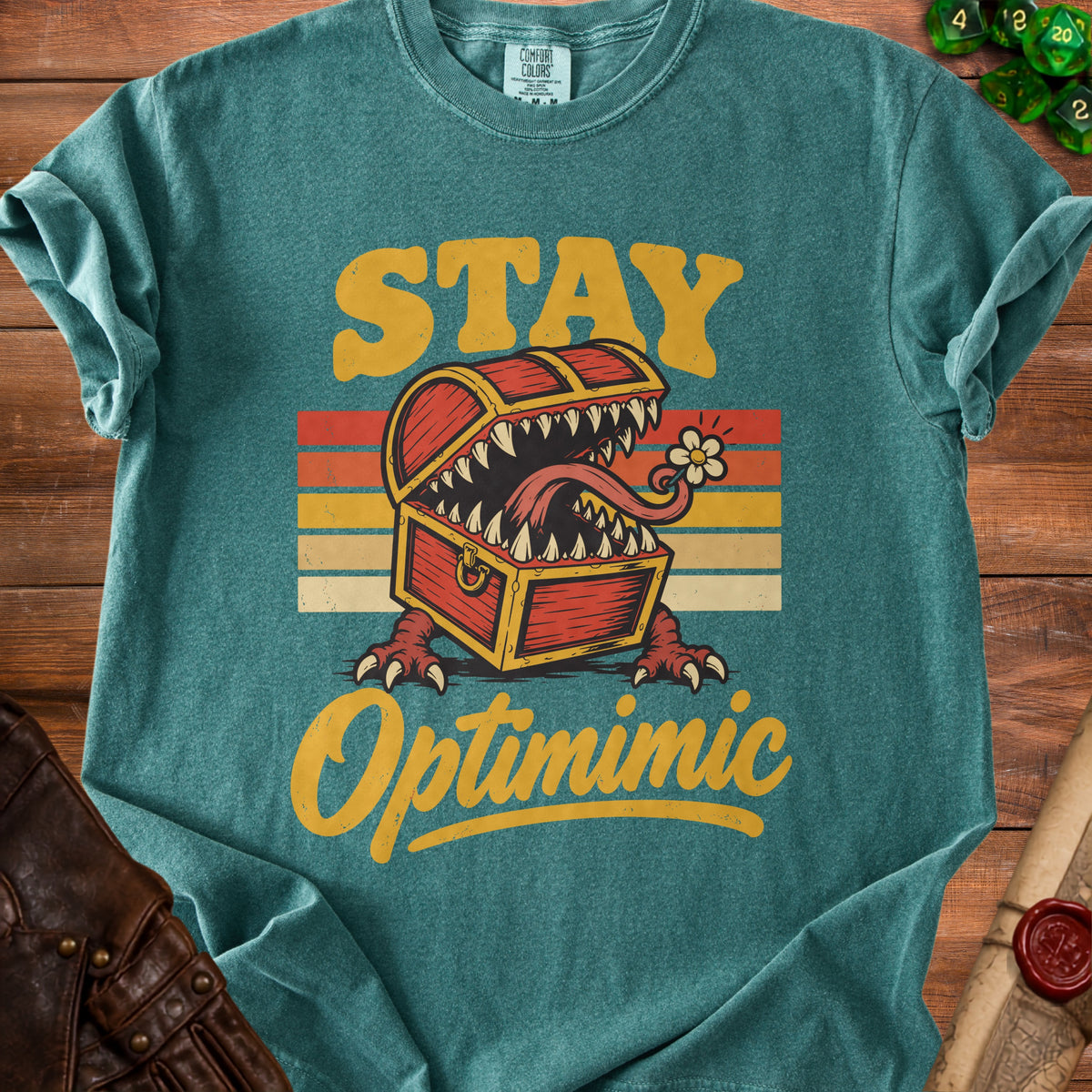 Teal t-shirt with "STAY Optimimic" text and a monster treasure chest.