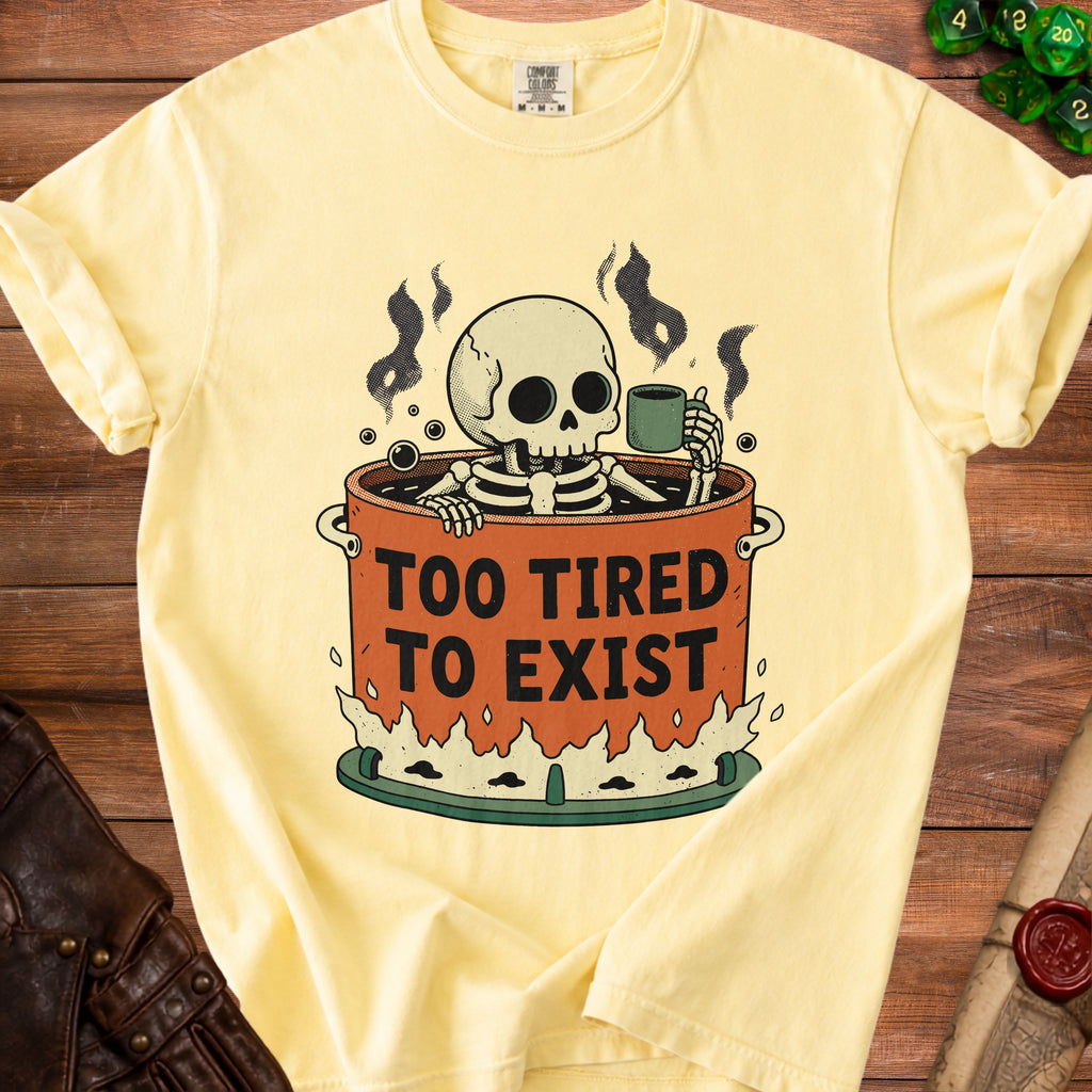 Yellow t-shirt with skeleton in cauldron graphic and text "TOO TIRED TO EXIST".