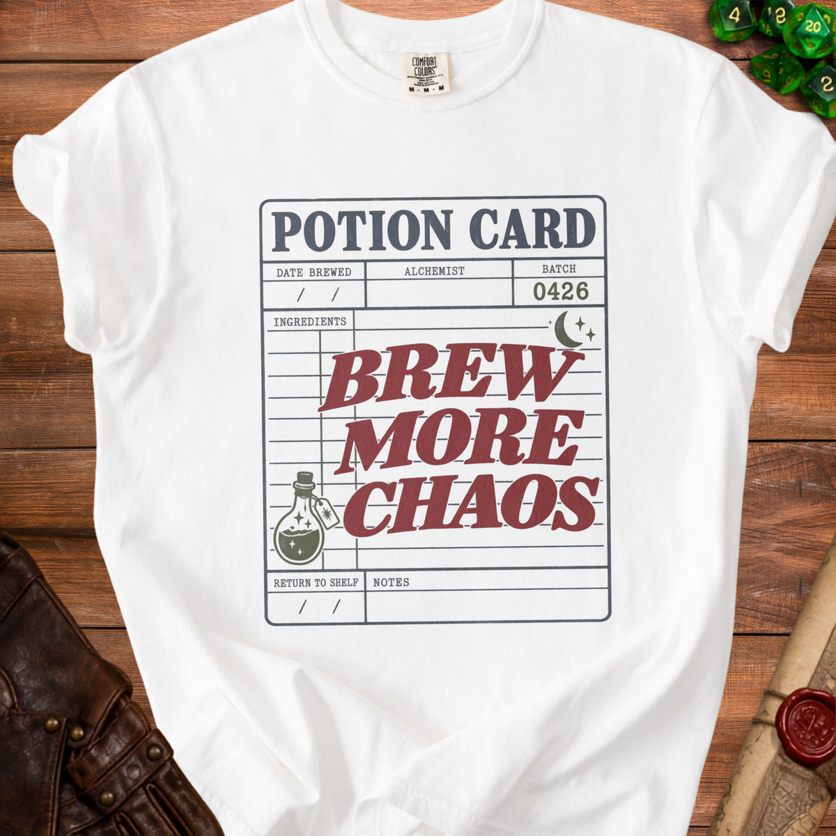 White t-shirt with a potion card graphic: "Brew More Chaos".