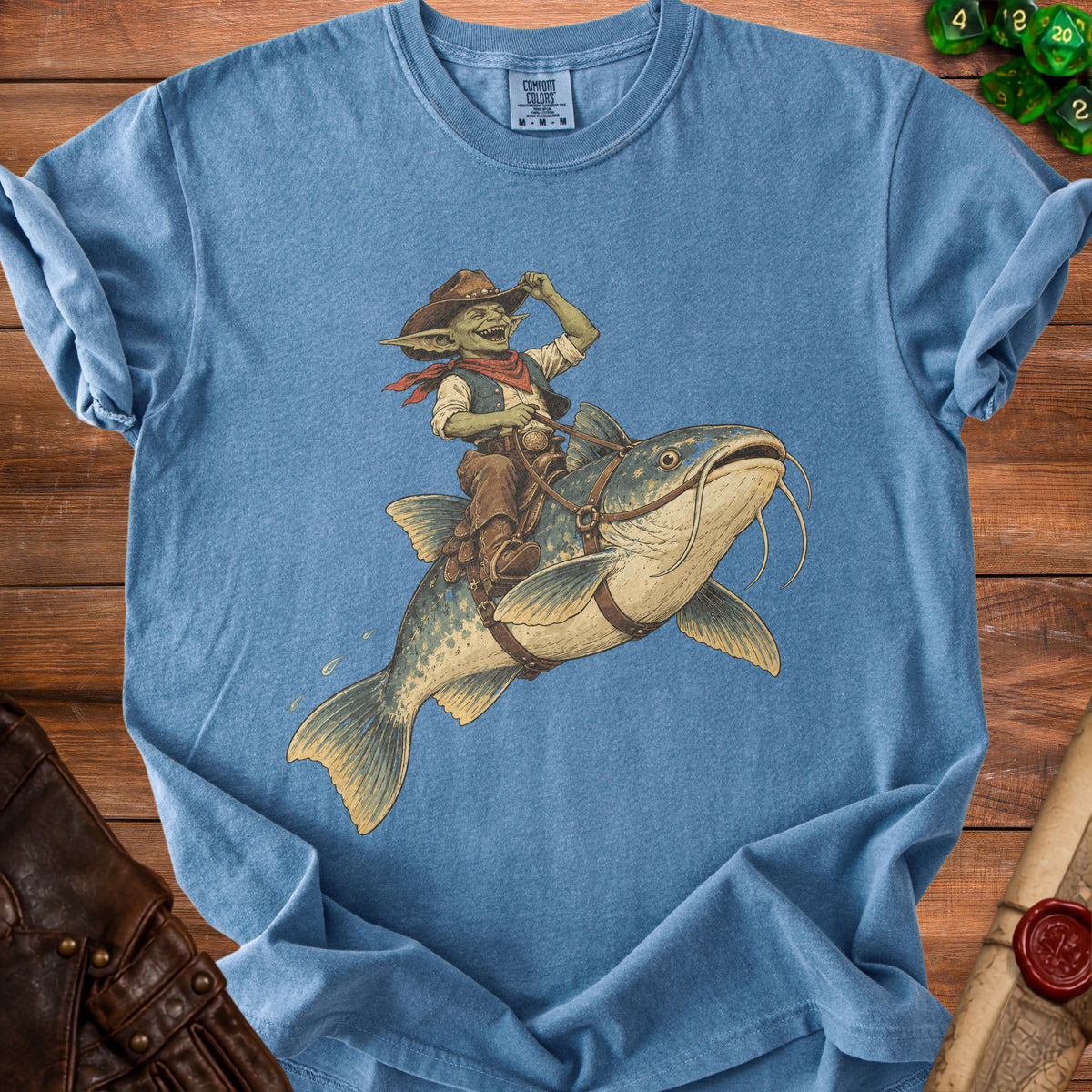 Goblin wearing a cowboy hat rides a catfish, printed on a blue t-shirt.