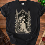 Black t-shirt with gothic art of a woman reading a scroll and a demon holding a quill.